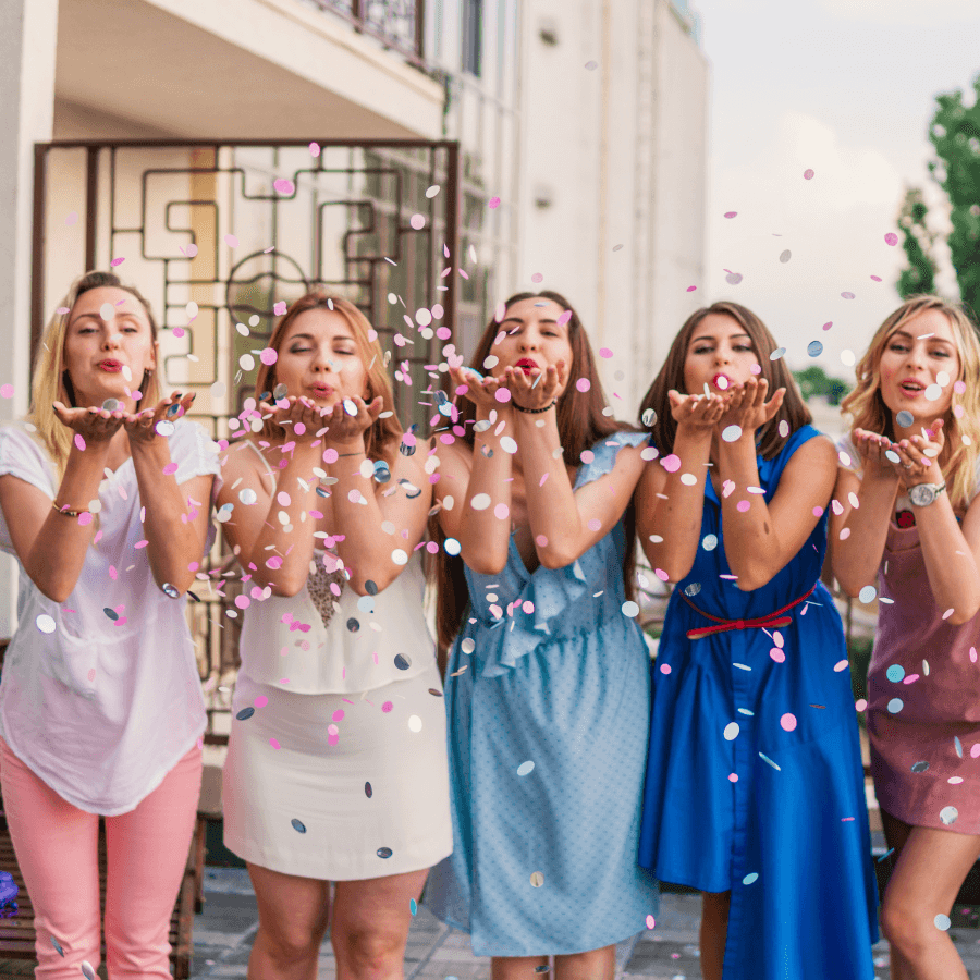 Bride and bridesmaids throwing confetti outside
