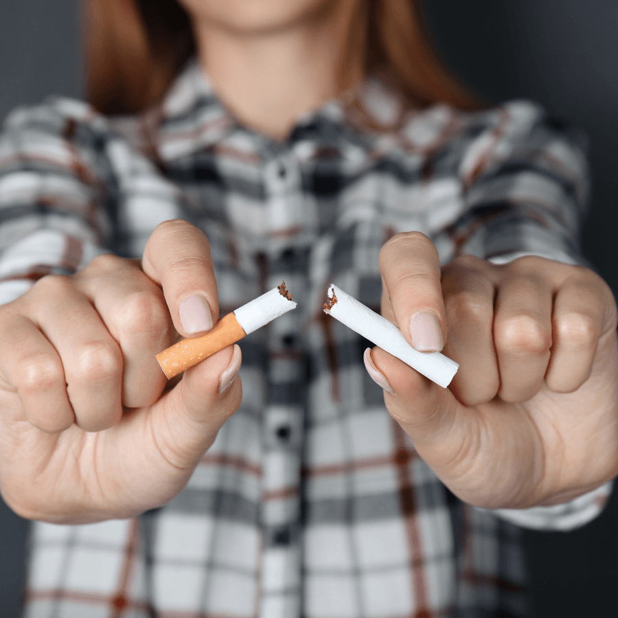 Woman in blue plaid shirt holding broken cigarette in front of her