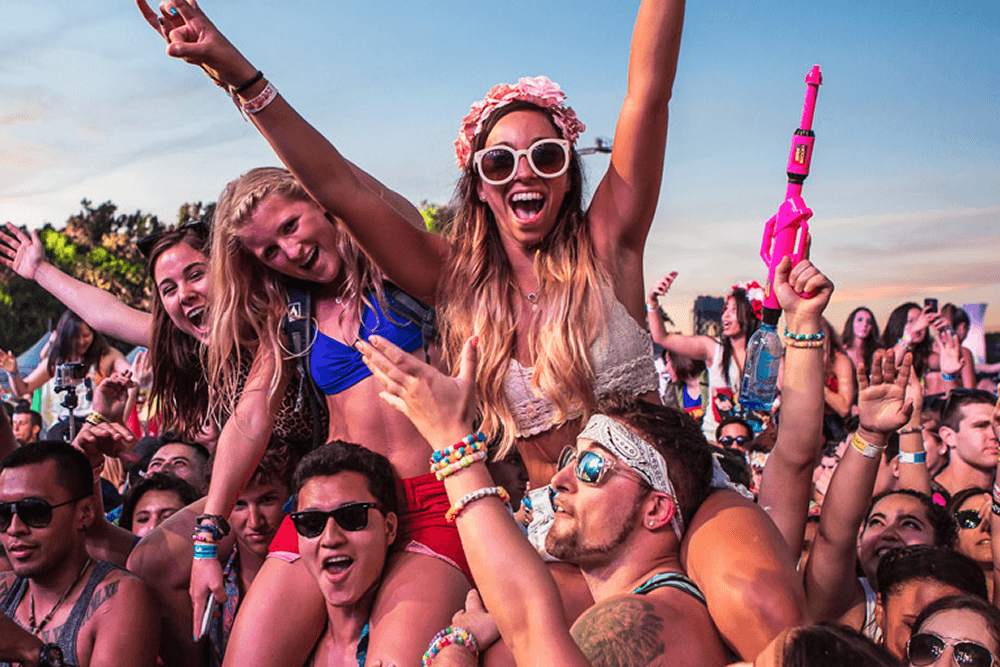 Young adults partying at festival, girls on guys shoulders
