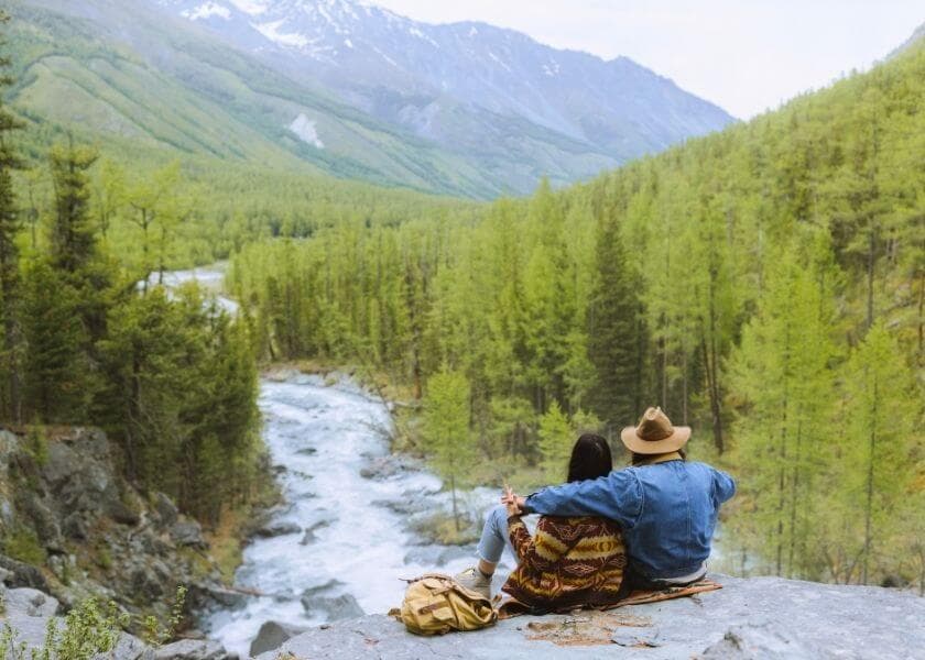 couple sitting on rock enjoying mountain view couple sitting on rock enjoying mountain view